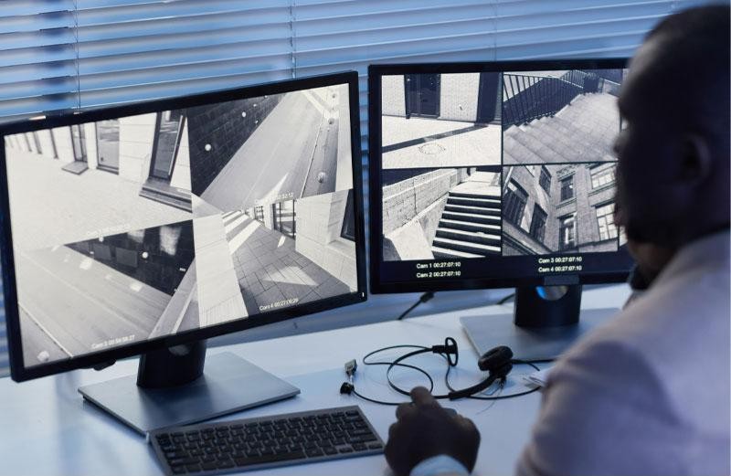 Security officer monitoring a commercial video surveillance system on dual screens